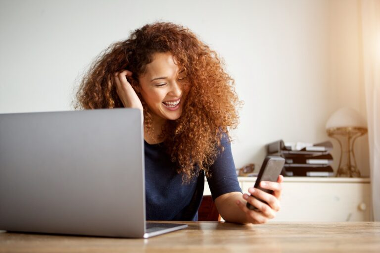 Portrait of happy young woman with laptop computer and mobile phone